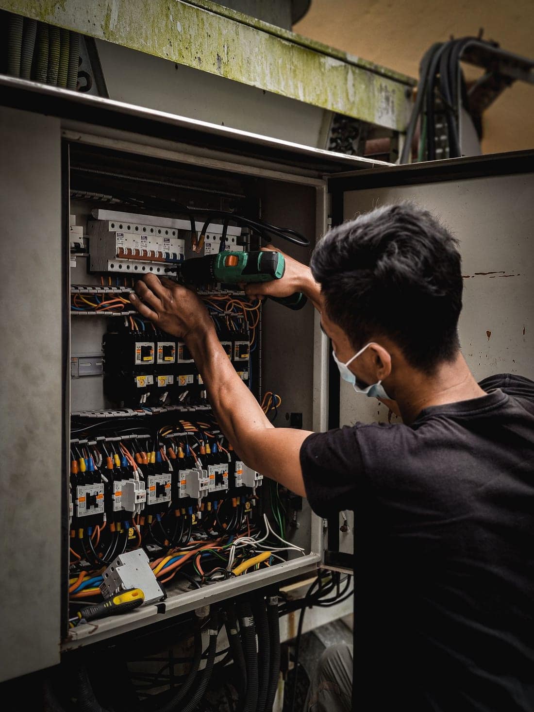Technician working on a circuit breaker distribution panel - the kind of MCB / RCCB upgrade most CIDCO flats need after 20-30 years of service