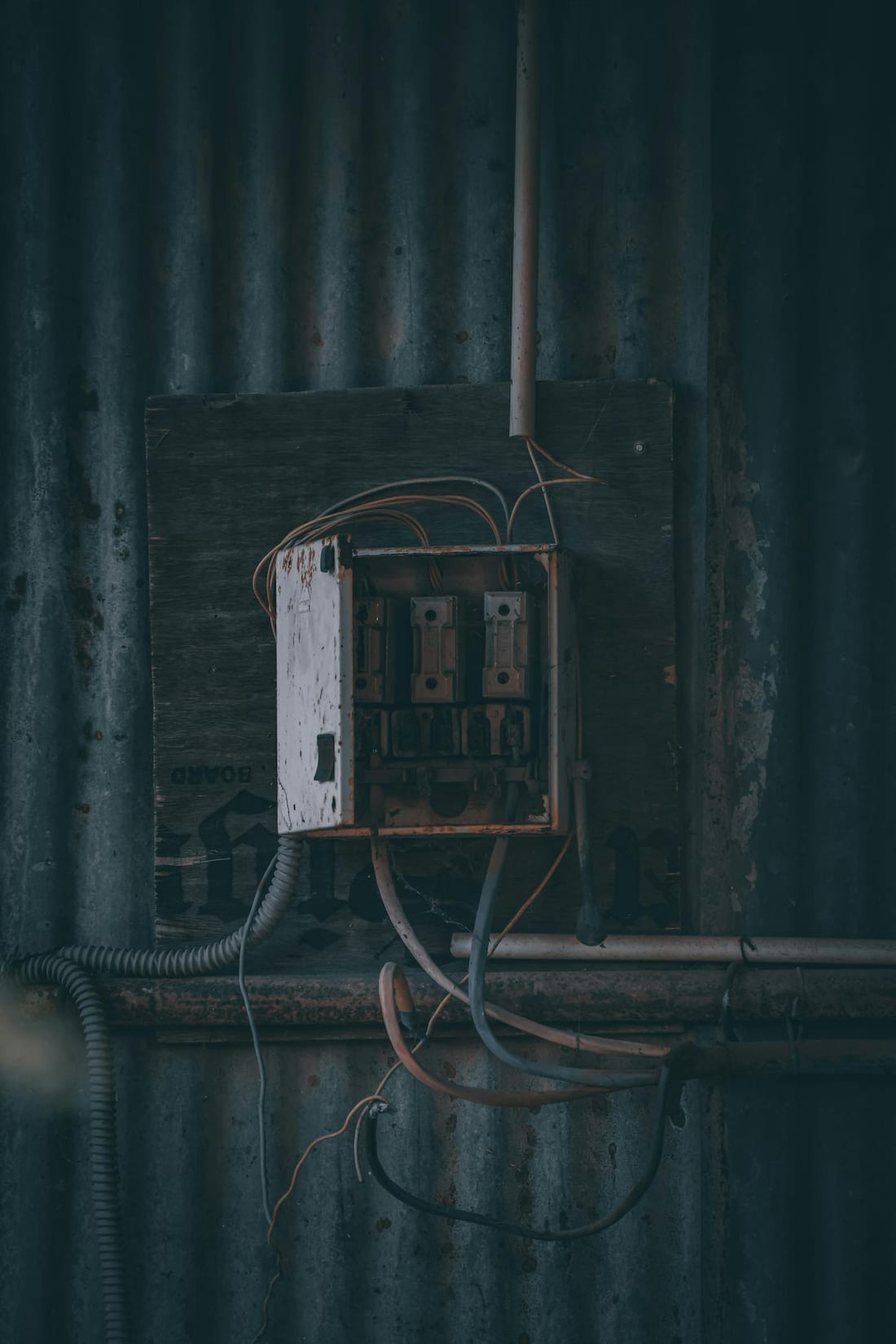Rusty electrical panel with exposed wires on a corrugated metal wall - the kind of degraded installation we upgrade in older Osmanpura buildings