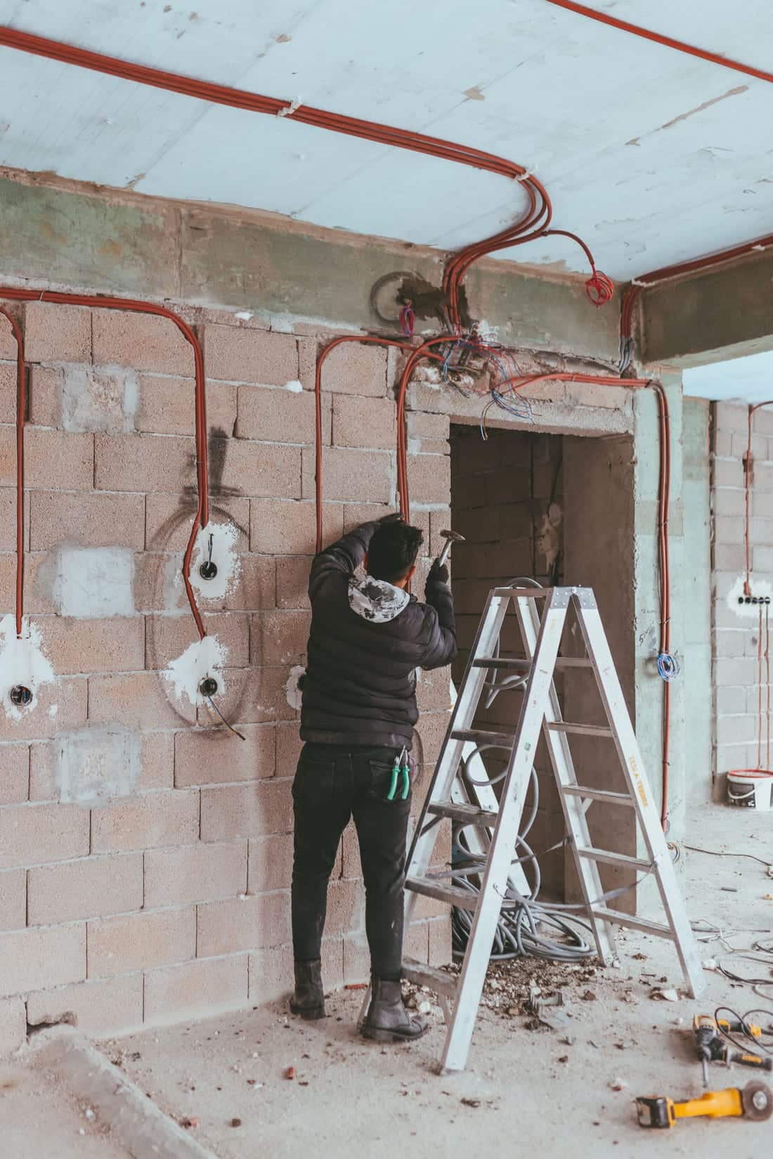 Electrician installing fresh wiring inside a building during a renovation - the kind of rewiring and dedicated AC / geyser circuit work we run in older Samarth Nagar plot houses