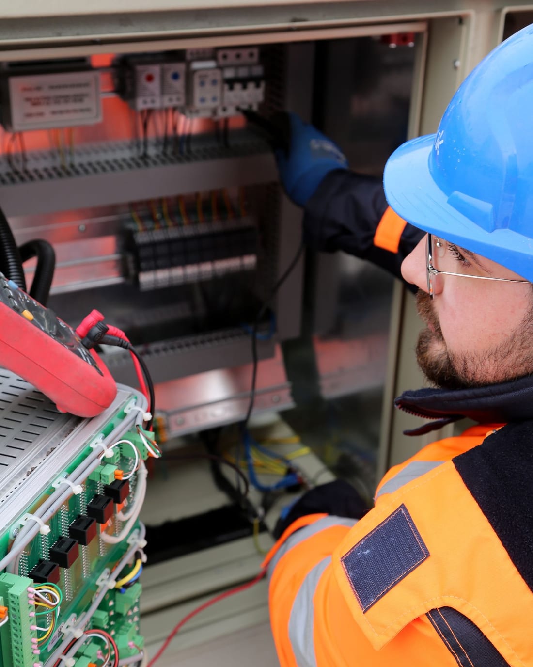 Electrician in safety gear working at an industrial switchboard panel in a factory - LT panel and AMC work Shaats Electrical does in Shendra MIDC units