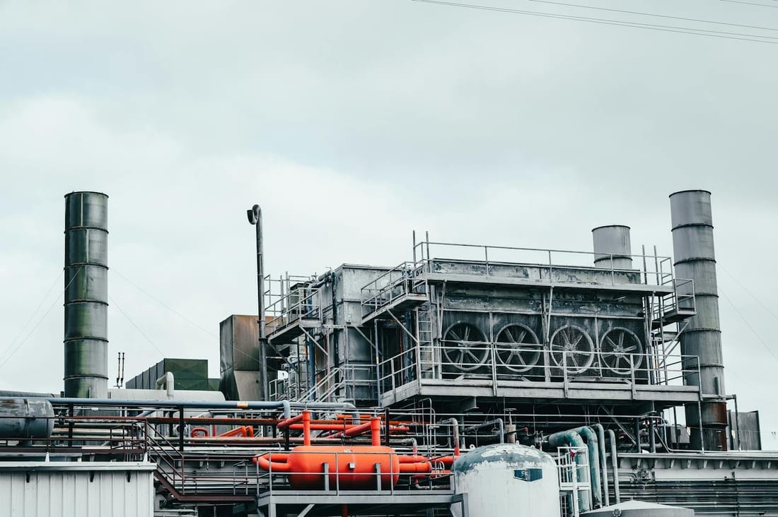 Factory interior with tall metal pipes and process equipment - the kind of three-phase, motor-heavy operation we keep running under AMC in Waluj MIDC