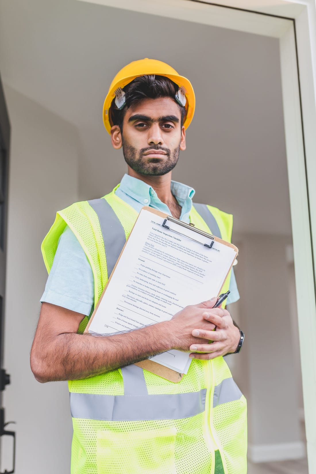 Industrial professional in hard hat holding a clipboard in a factory - the written visit report and checklist approach that makes an electrical AMC documented and auditable
