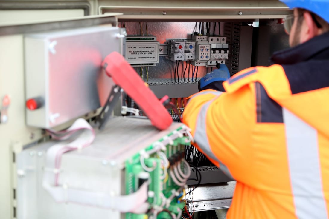 Indian electrical engineer checking an industrial control panel during a planned annual maintenance visit