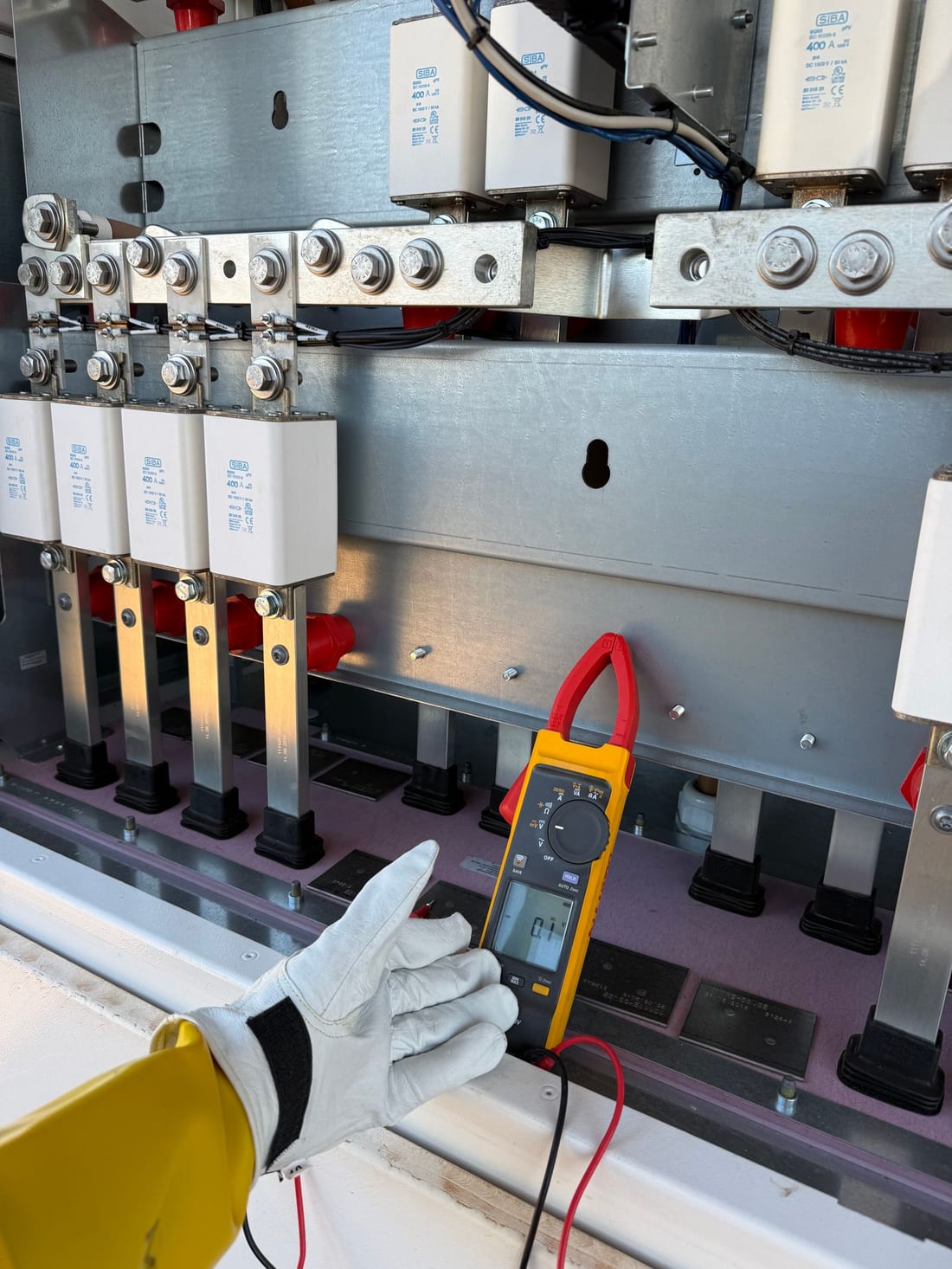 Indian technician inspecting circuit breakers inside a distribution panel during a scheduled maintenance visit