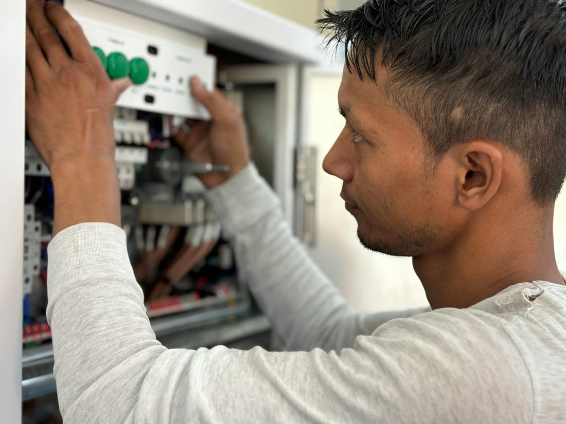 Indian technician adjusting MCBs inside a hotel distribution panel during a scheduled preventive maintenance visit