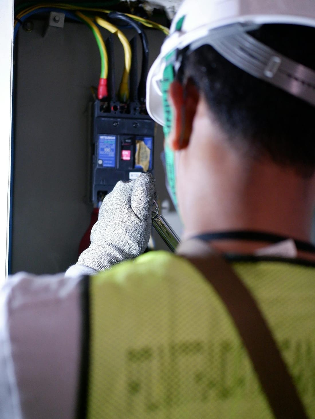 Electrician wearing insulated gloves operating a residential CB panel - pre-monsoon RCCB test and panel safety check