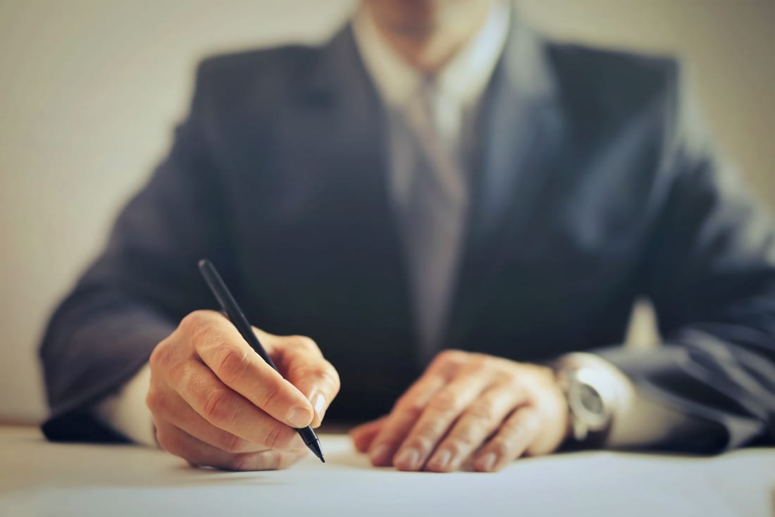 A contract document being signed at a desk - the work order stage that follows tendering or direct procurement in government electrical work