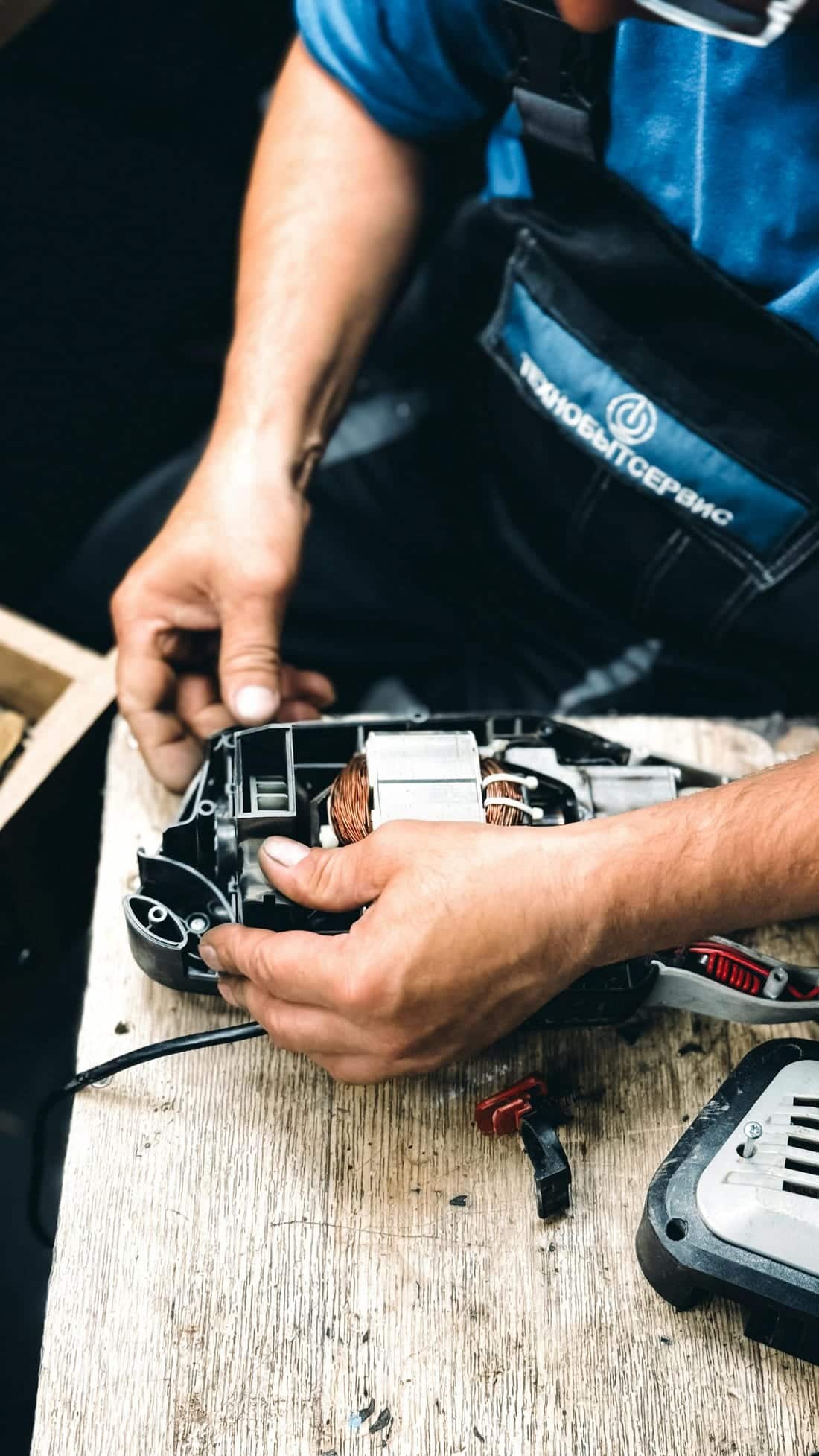 Technician inspecting an electrical tool / motor end on a wooden bench - typical motor diagnostic moment during a Shaats Electrical workshop visit