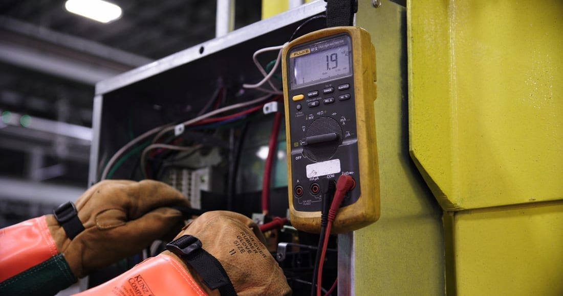 Engineer using a multimeter on a distribution panel to verify pre-monsoon readings - voltage stability and earth-pit resistance check