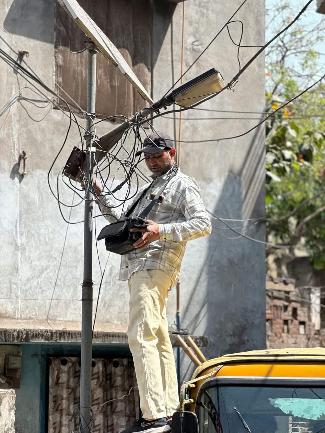 Indian electrician on a pole repairing outdoor electrical fixtures before the monsoon - Shaats Electrical pre-monsoon audit in Chh. Sambhajinagar (Aurangabad)