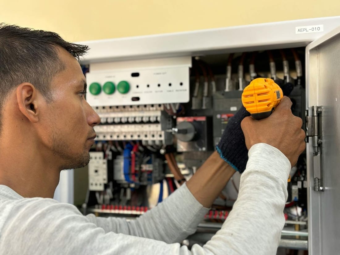 Indian electrician using a power drill on a hotel electrical fixture during an emergency repair call