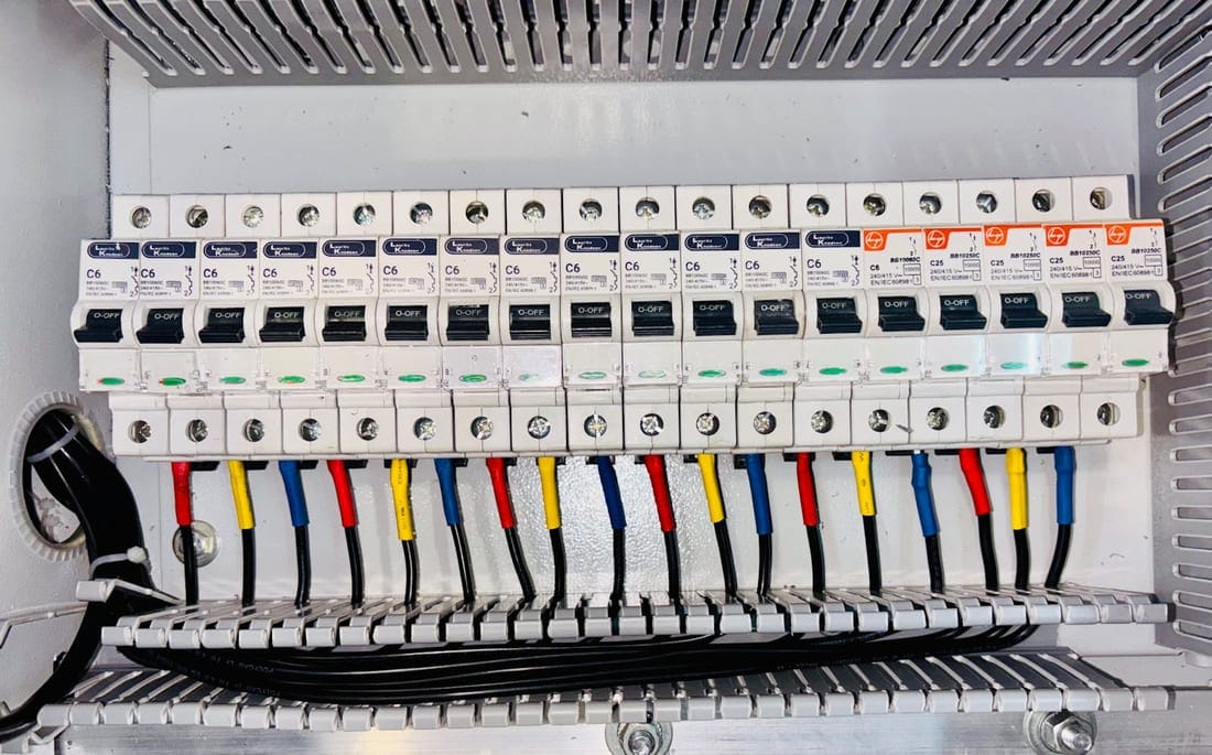 Neatly organized distribution panel with color-coded wiring - proper earth conductors (green/green-yellow) visible alongside phase and neutral