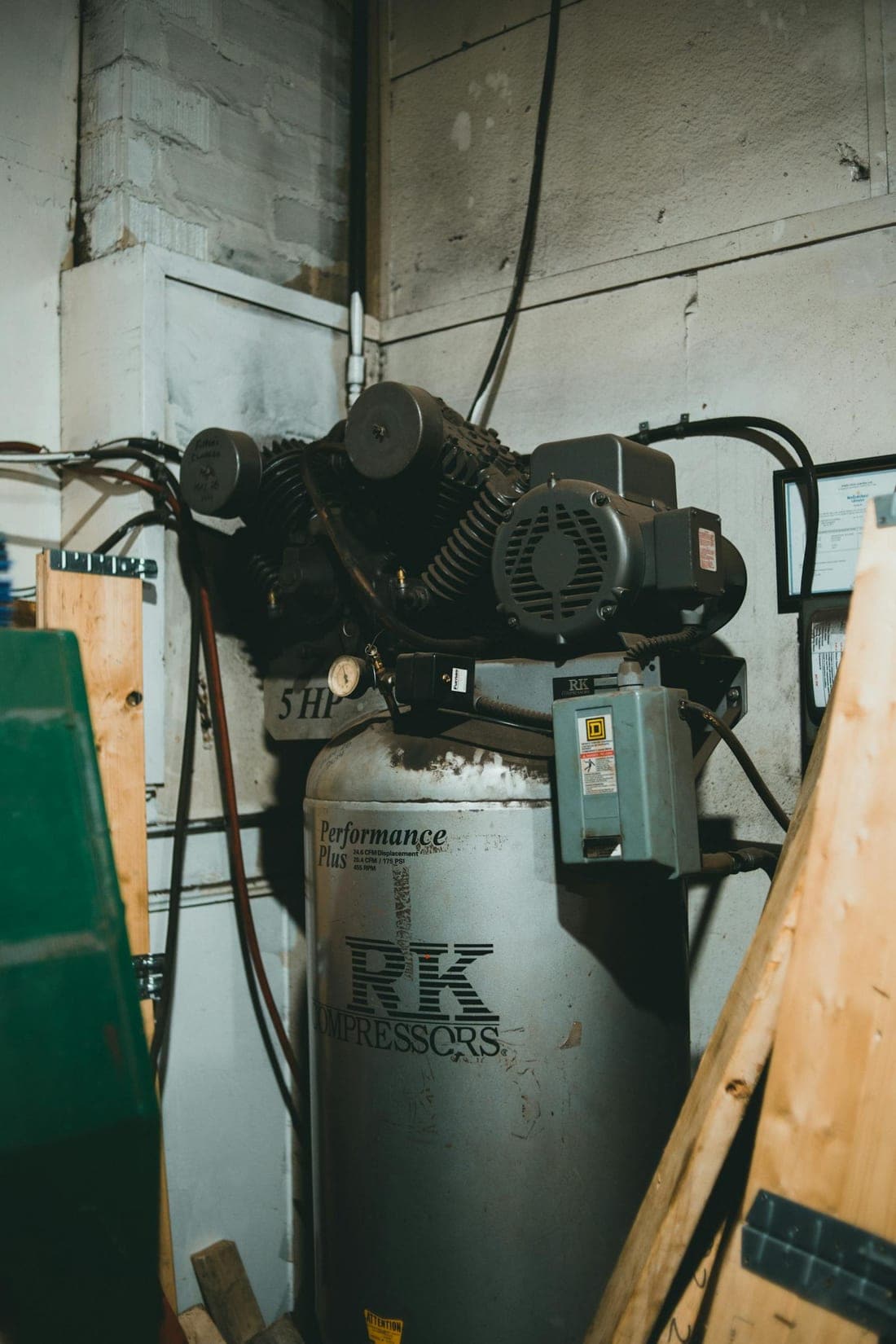 Large industrial air compressor with its motor inside a small workshop - the kind of high-inertia load that needs proper starter selection to avoid motor burnout