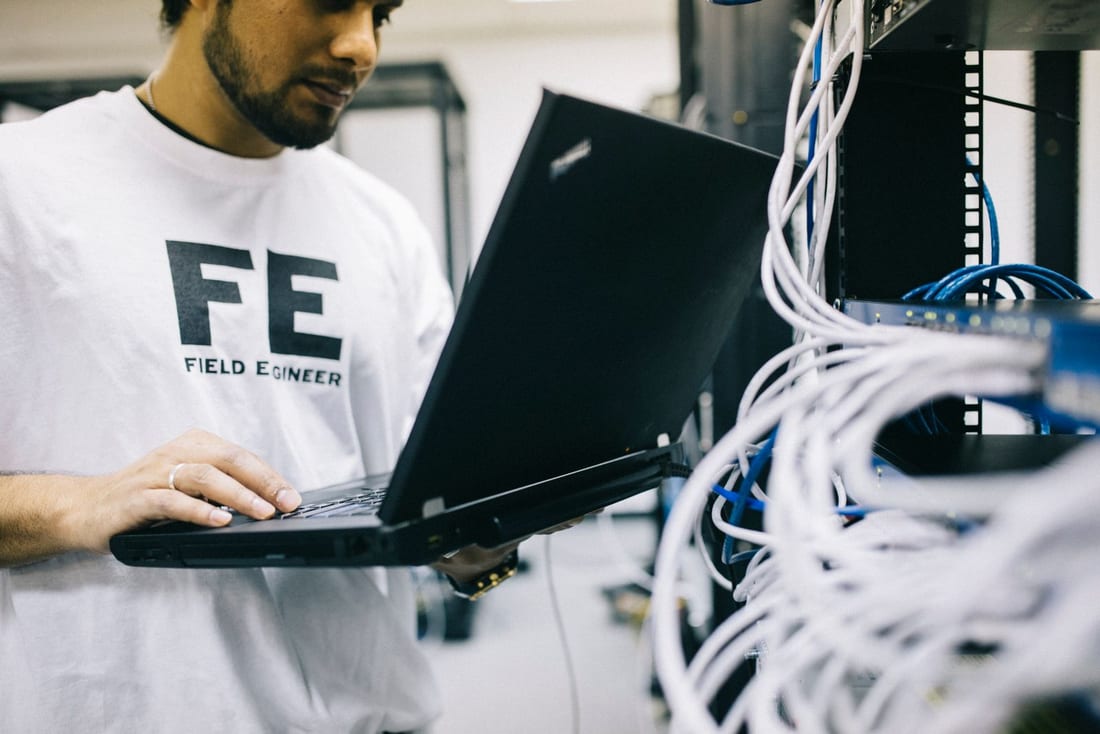 Engineer verifying a system with a laptop during commissioning - the documentation and testing discipline Shaats Electrical applies on CCTV, panel and EV charger handovers