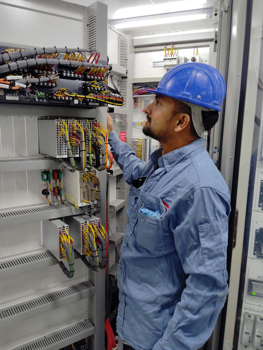 New electrical installation in Chhatrapati Sambhajinagar (Aurangabad) — Indian electrician in safety helmet inspecting a freshly wired distribution panel