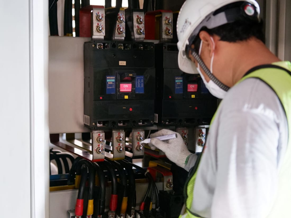 Technician in safety gear inspecting electrical distribution panels during a scheduled preventive maintenance visit - electrical AMC service for Waluj MIDC factories in Chh. Sambhajinagar