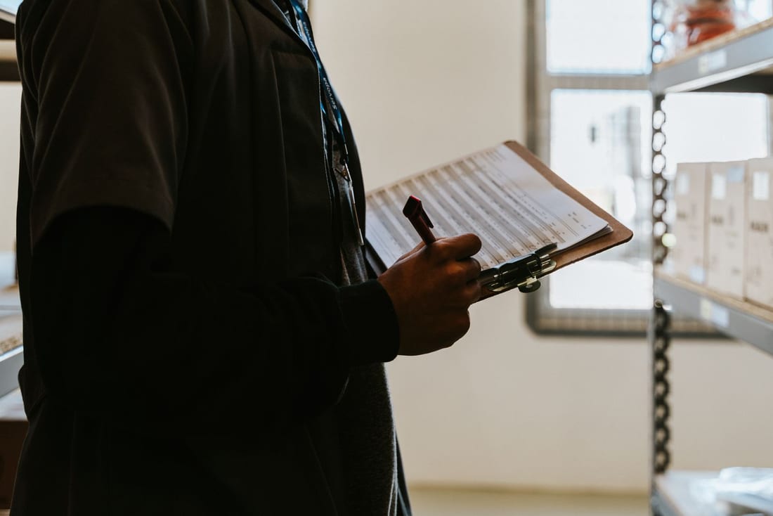 Industrial worker with a checklist clipboard in a factory setting - the documented, checklist-based approach used during every Shendra MIDC AMC visit